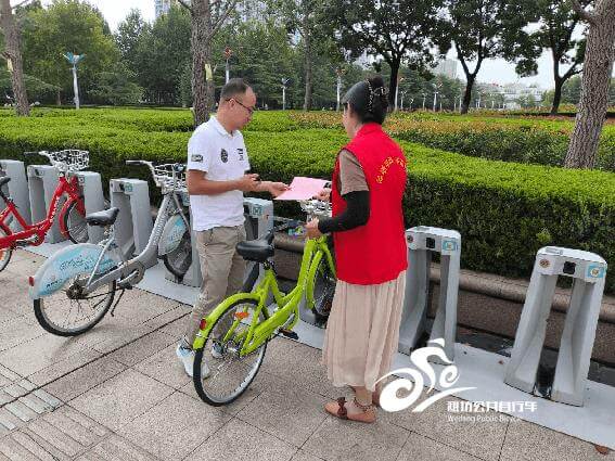 志愿者在公共自行车站点向市民宣传绿色出行